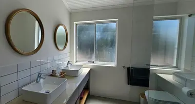 a bathroom with two sinks and a mirror at Tamatiebank in Hermanus