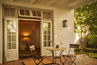 a patio with a table and chairs next to a door at Leeu House in Franschhoek