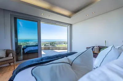 a bedroom with a bed and a view of the ocean at Dolphin View Cabana Beach House in Cape Town