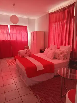 a bedroom with a large bed with red curtains at Lucian Bed and Breakfast in Goodwood