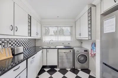 a white kitchen with a washing machine in it at The Island Beach House in Cape Town