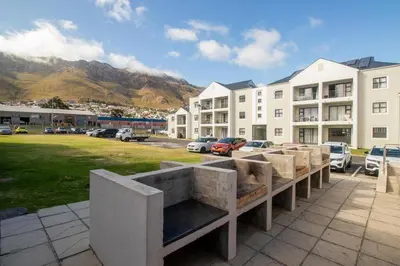 a group of benches in a parking lot with buildings at 118 on the Bay in Gordonʼs Bay