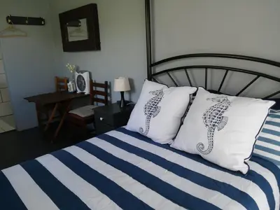 a bed with blue and white striped sheets and pillows at Pik 'n Wyntjie in Bettyʼs Bay