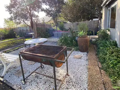 a barbecue grill and a chair in a garden at Pik 'n Wyntjie in Bettyʼs Bay