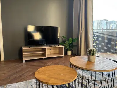 a living room with a flat screen tv and two tables at Modern chic at On park Century City near Canal Walk in Cape Town