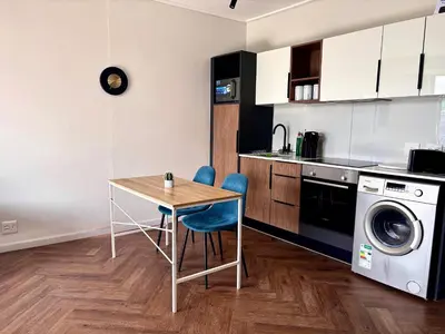 a kitchen with a table and a washing machine at Modern chic at On park Century City near Canal Walk in Cape Town