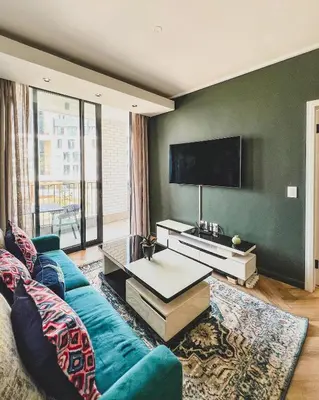 a living room with a blue couch and a flat screen tv at Agape Apartment On park Century in Cape Town