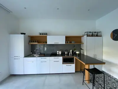 a kitchen with white cabinets and a black counter top at Stellenbosch Rozendal Apartment in Stellenbosch