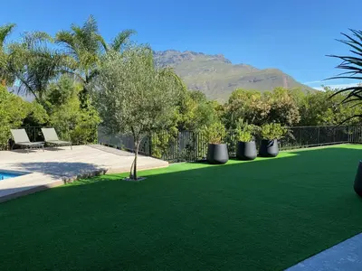 a yard with green artificial grass and a fence at Stellenbosch Rozendal Apartment in Stellenbosch