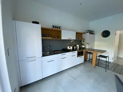 a kitchen with white cabinets and a table in it at Stellenbosch Rozendal Apartment in Stellenbosch