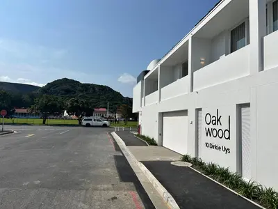 a white building with a oak wood utility sign on it at Central Town Duplex with Pool, BBQ & Mountain View in Hermanus
