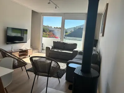 a living room with a couch and a tv at Central Town Duplex with Pool, BBQ & Mountain View in Hermanus