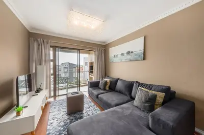 a living room with a couch and a tv at Modern City Apartment with Balcony & Braai in Cape Town