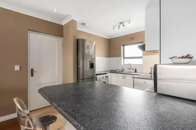 a kitchen with a black counter top in a room at Modern City Apartment with Balcony & Braai in Cape Town