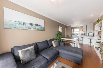 a living room with a couch and a kitchen at Modern City Apartment with Balcony & Braai in Cape Town