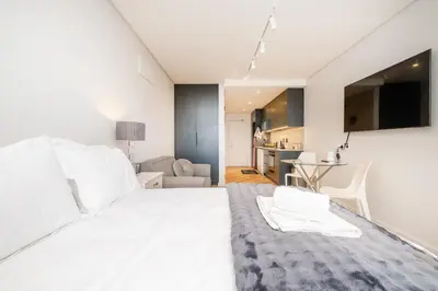 a bedroom with a white bed and a living room at Paarl Studio With Onsite Parking & Modern Comforts in Paarl