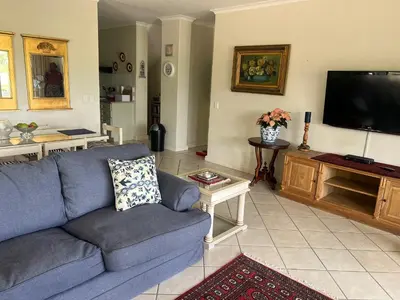 a living room with a blue couch and a flat screen tv at Golfers paradise on 25th green in Hermanus