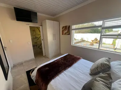 a bedroom with a large bed and a window at Minak Guest House Bellville in Bellville