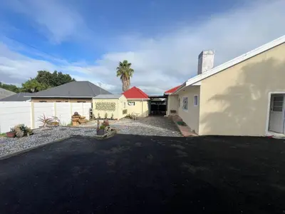 a driveway in front of a house with a palm tree at Minak Guest House Bellville in Bellville