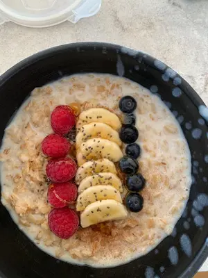 a bowl of oatmeal with fruit and bananas and berries at Tide and Timber Luxury Guesthouse in Hermanus