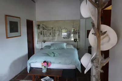 a bedroom with a bed and a table with flowers on it at The Little Gallery in Villiersdorp