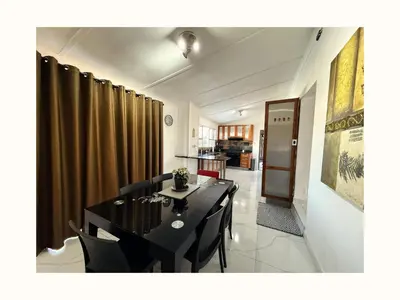 a dining room with a black table and chairs at Rihla Residences - Civic Road in Cape Town