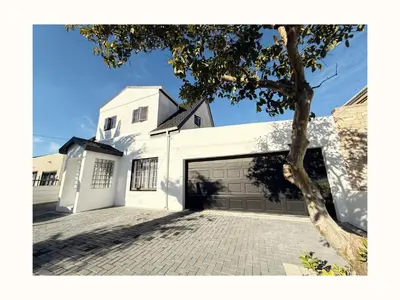 a white house with a garage and a tree at Rihla Residences - Civic Road in Cape Town