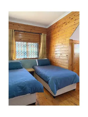two beds in a room with wooden walls at Rihla Residences - Civic Road in Cape Town