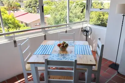 a table with chairs and a bowl of fruit on a balcony at Stylish Apartment in Hermanus in Hermanus
