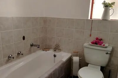 a bathroom with a tub and a toilet with flowers on it at Stylish Apartment in Hermanus in Hermanus