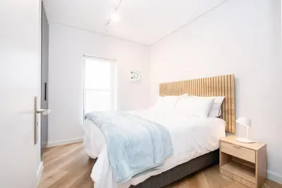 a white bedroom with a large bed and a window at Paarl - Lux Modern 2 Bedroom Apartment with Parking in Paarl