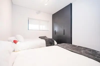 a bedroom with two beds and a black cabinet at Paarl - Lux Modern 2 Bedroom Apartment with Parking in Paarl
