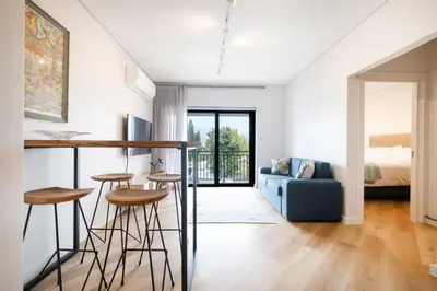 a kitchen and living room with a blue couch and stools at Paarl - Lux Modern 2 Bedroom Apartment with Parking in Paarl
