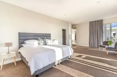 a white bedroom with a large bed and a chair at Modern Home with Views, Pool & Fireplaces in Estate in the Wineland