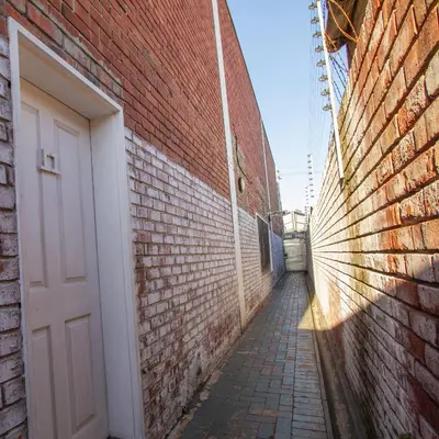 an alley with a white door and a brick wall at Lodge Luxe, Cozy Bedrooms, Free WiFi, Robust Security in Cape Town