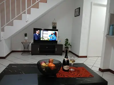 a living room with a television and a bowl of fruit at Fisherman's Haven in Bloubergstrand