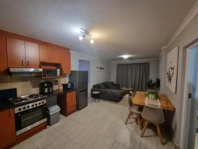 a kitchen and living room with a table and a couch at 180 Mont Blanc in Gordonʼs Bay