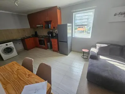 a kitchen and living room with a couch and a table at 180 Mont Blanc in Gordonʼs Bay