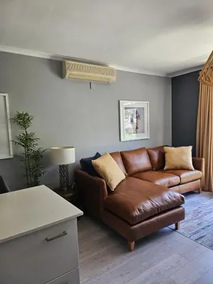 a living room with a brown couch and a table at At Leisure Apartment 2 in Stellenbosch