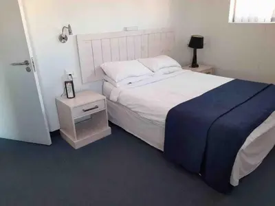 a bedroom with a bed with a blue blanket and a night stand at 401 Pip's Place in Strand