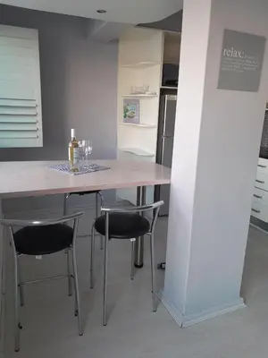 a kitchen with a table and chairs with wine glasses on it at 401 Pip's Place in Strand