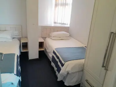 a small room with two beds and a window at 401 Pip's Place in Strand
