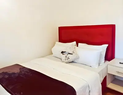 a bed with a red headboard and white pillows at Peace Accommodation B&B in Silver Sands