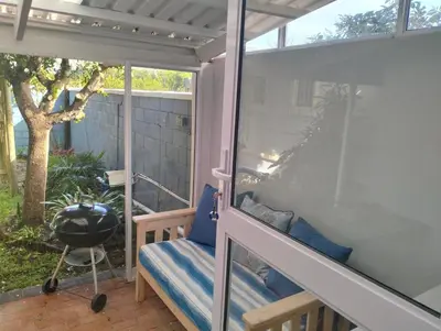 a screened in porch with a bench and a grill at Garden es Cape in Pringle Bay