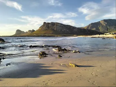 a sandy beach with mountains in the background at Garden es Cape in Pringle Bay
