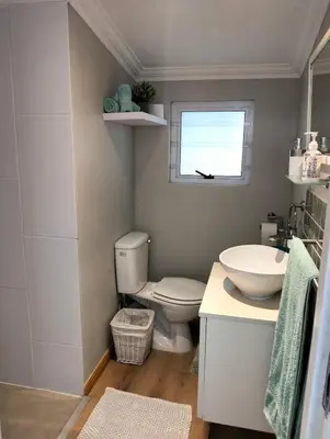 a bathroom with a toilet and a sink and a window at Garden es Cape in Pringle Bay