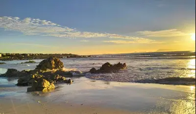 a beach with rocks in the water and the ocean at Garden es Cape in Pringle Bay