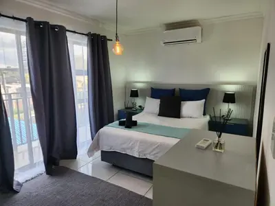 a bedroom with a bed with blue pillows and a window at G's Apartments Cape Town in Windsor Park