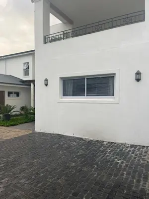 a white house with a window and a brick driveway at Spacious Bachelor Die Boord in Stellenbosch