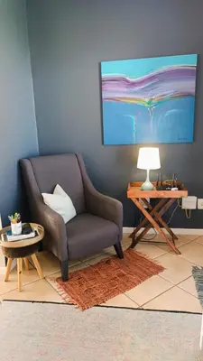 a living room with a chair and a table at Entire 2 Level Townhouse in Backenfell Cape Town in Brackenfell